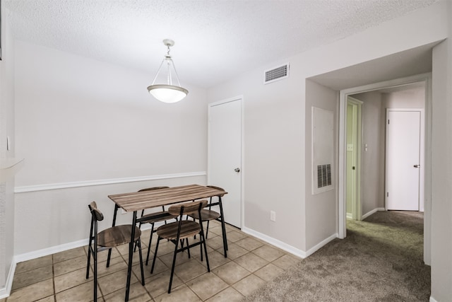 dining room featuring light carpet and a textured ceiling