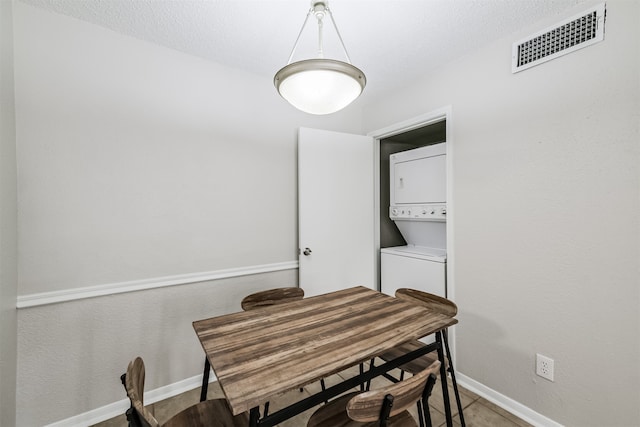 dining room with a textured ceiling and stacked washer and dryer