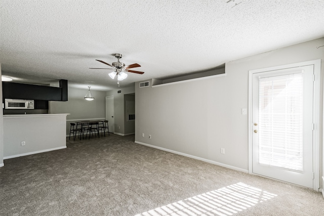 unfurnished living room with ceiling fan, a textured ceiling, and carpet flooring