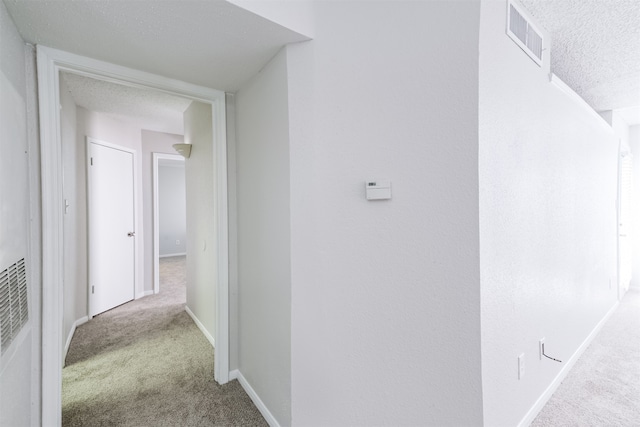 hallway with a textured ceiling and carpet flooring