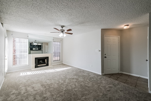 unfurnished living room with ceiling fan, a textured ceiling, and carpet