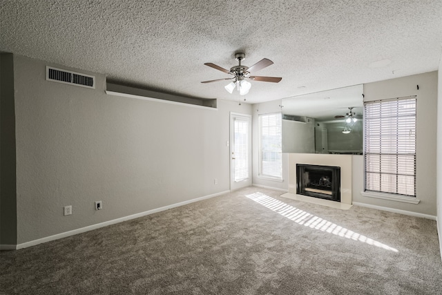 unfurnished living room with carpet flooring, ceiling fan, a healthy amount of sunlight, and a textured ceiling