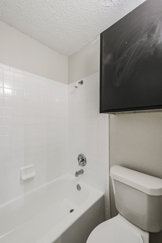 bathroom featuring a textured ceiling, tiled shower / bath combo, and toilet