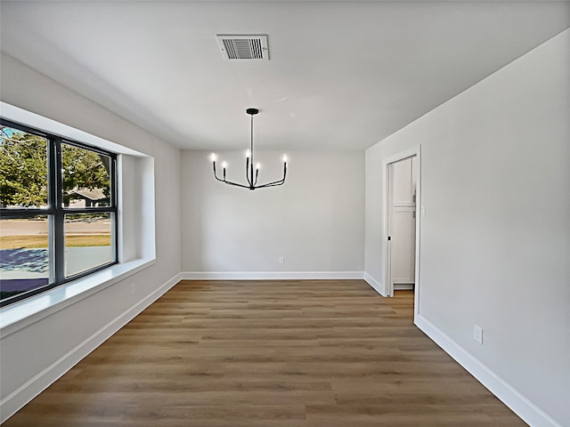 unfurnished dining area featuring an inviting chandelier and dark hardwood / wood-style floors