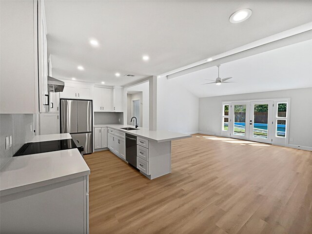 5743 Ludington Dr, Houston, TX 77035 - kitchen with white cabinets, a peninsula, freestanding refrigerator, wall chimney range hood, and dishwasher