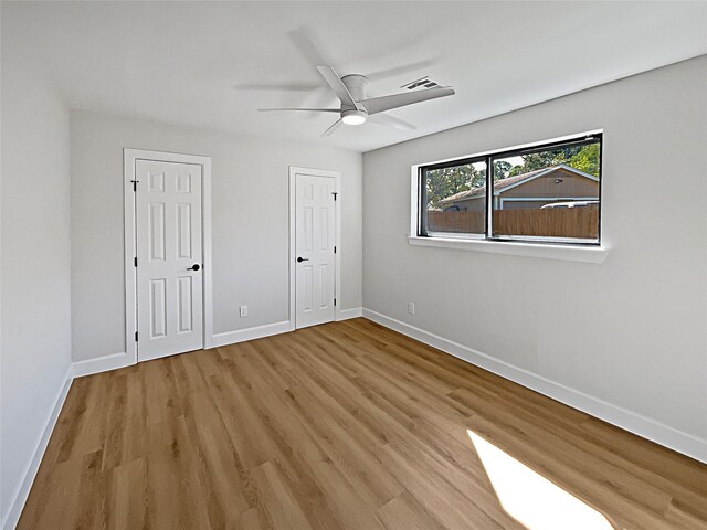 5743 Ludington Dr, Houston, TX 77035 - unfurnished bedroom featuring two closets, ceiling fan, baseboards, and wood finished floors