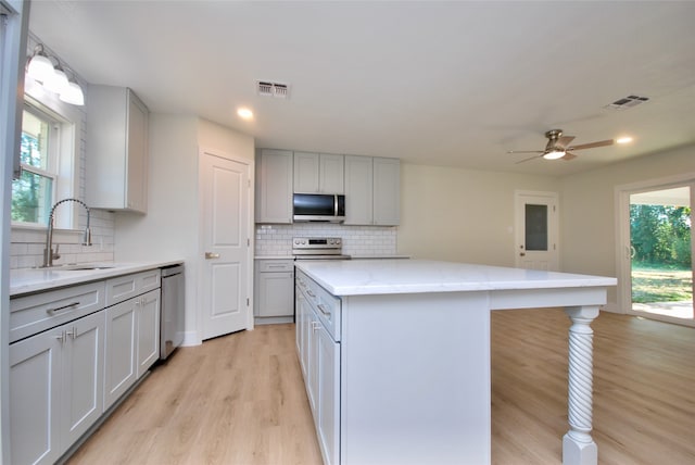 kitchen featuring gray cabinets, stainless steel appliances, a center island, light hardwood / wood-style flooring, and sink