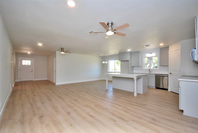 kitchen featuring light hardwood / wood-style floors, tasteful backsplash, a kitchen island, appliances with stainless steel finishes, and ceiling fan