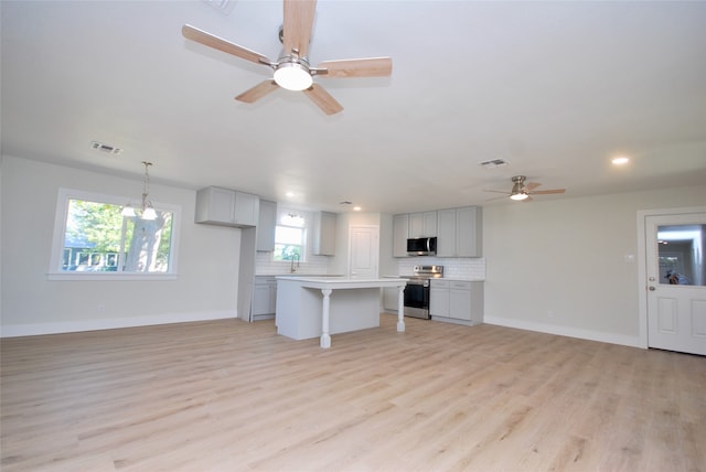 kitchen featuring gray cabinets, light hardwood / wood-style floors, a center island, tasteful backsplash, and stainless steel appliances