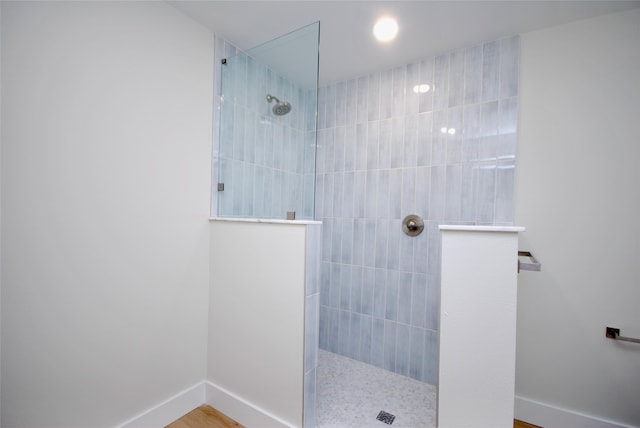 bathroom featuring wood-type flooring and a tile shower