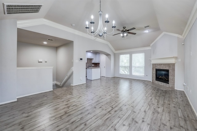 unfurnished living room with vaulted ceiling, light wood-type flooring, and ornamental molding