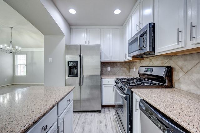 kitchen featuring appliances with stainless steel finishes, decorative light fixtures, light stone countertops, and white cabinets