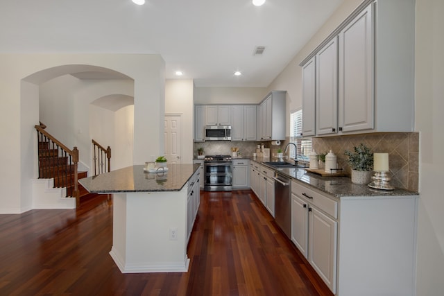 kitchen featuring dark stone countertops, stainless steel appliances, dark hardwood / wood-style floors, and sink