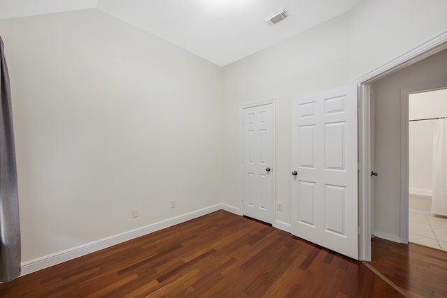 unfurnished bedroom with lofted ceiling and dark hardwood / wood-style floors