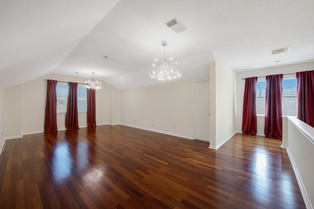 unfurnished living room with lofted ceiling, dark hardwood / wood-style floors, a chandelier, and a wealth of natural light