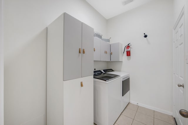 washroom with cabinets, light tile patterned floors, and washing machine and dryer