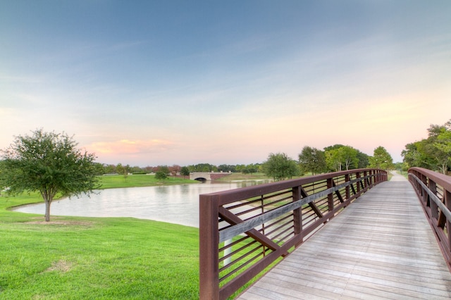 view of dock with a lawn and a water view