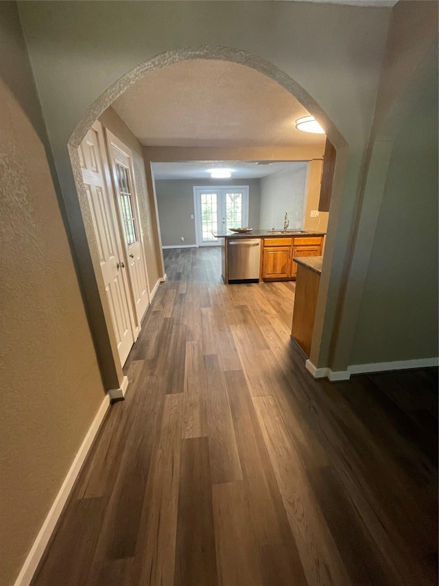 hall featuring wood-type flooring, a textured ceiling, french doors, and sink