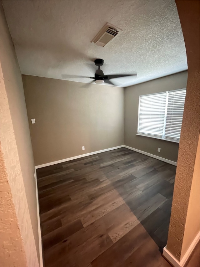 spare room with ceiling fan, dark hardwood / wood-style floors, and a textured ceiling