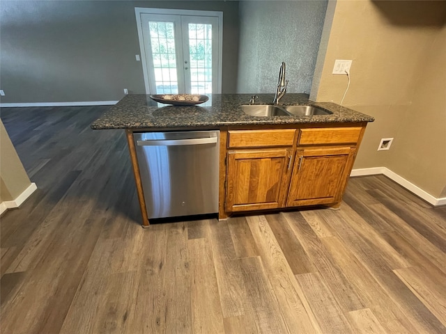 kitchen with dark stone counters, stainless steel dishwasher, sink, and hardwood / wood-style flooring