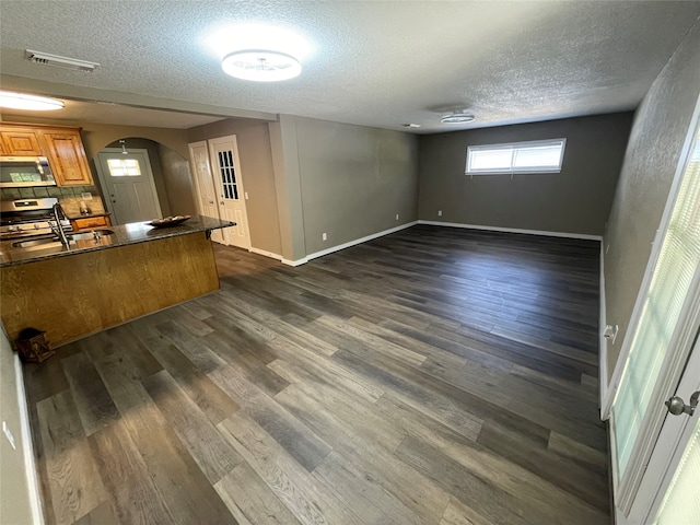 interior space featuring stainless steel appliances, a textured ceiling, dark wood-type flooring, and sink