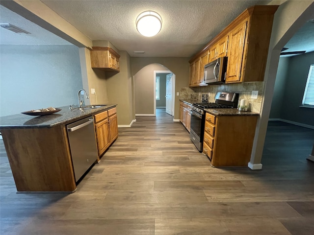 kitchen with a textured ceiling, stainless steel appliances, sink, and hardwood / wood-style floors