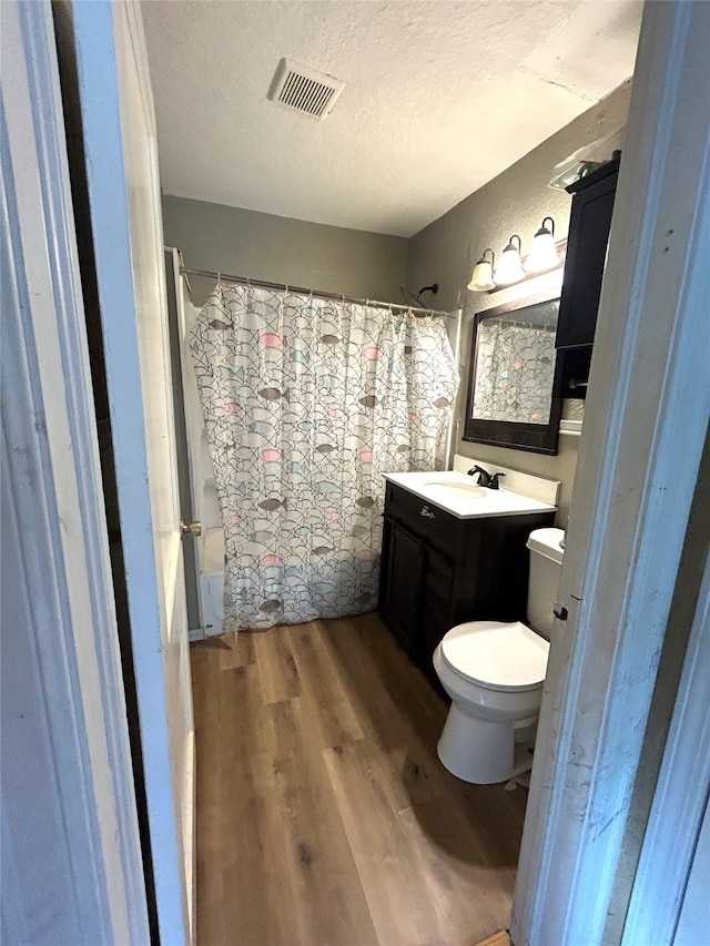 bathroom featuring a textured ceiling, a shower with shower curtain, hardwood / wood-style floors, vanity, and toilet