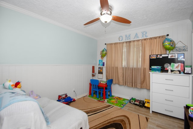 bedroom with a textured ceiling, crown molding, ceiling fan, and light hardwood / wood-style flooring