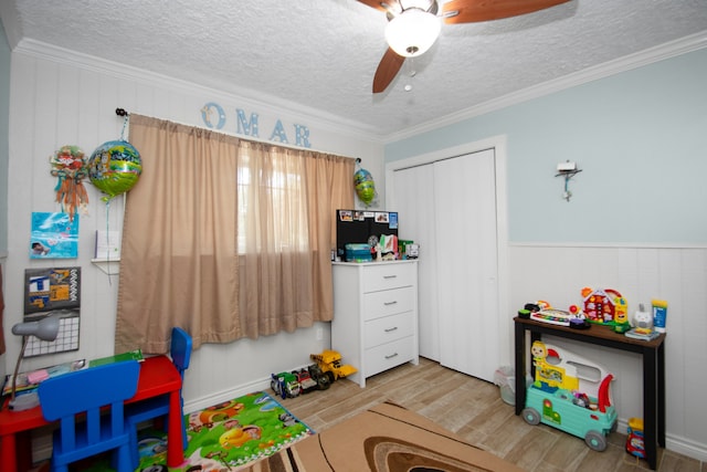 recreation room featuring a textured ceiling, crown molding, ceiling fan, and light hardwood / wood-style flooring