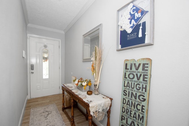 entrance foyer with a textured ceiling, light hardwood / wood-style floors, and crown molding