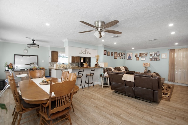 dining space featuring light hardwood / wood-style floors, ceiling fan, and a textured ceiling