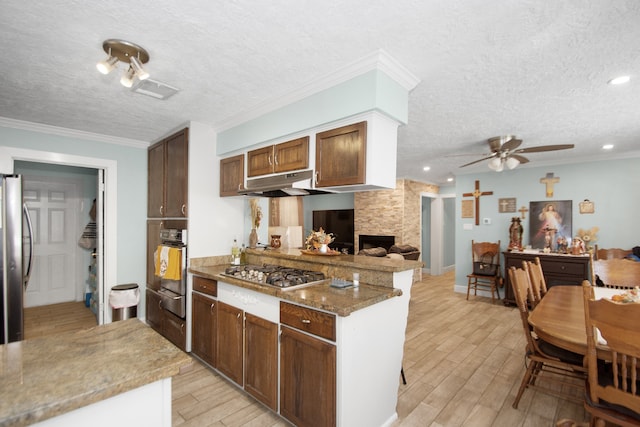 kitchen featuring light hardwood / wood-style flooring, stainless steel appliances, a textured ceiling, and ornamental molding