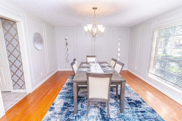 dining space with light hardwood / wood-style flooring, a chandelier, and a textured ceiling