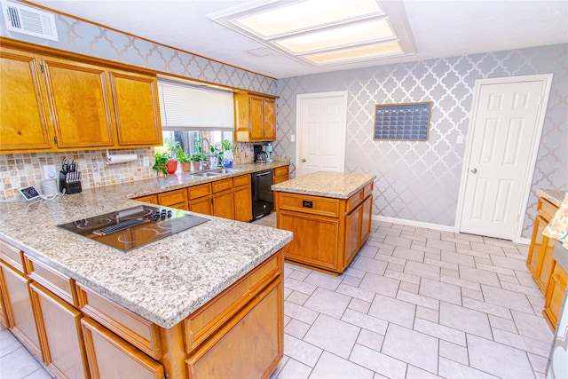 kitchen featuring light stone counters, sink, a kitchen island, black appliances, and decorative backsplash