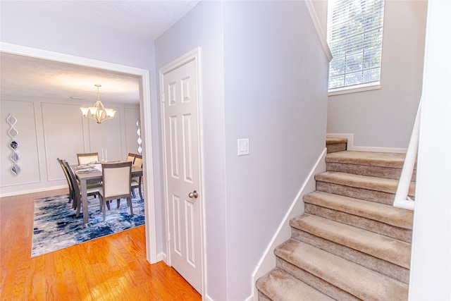 stairway with wood-type flooring, a notable chandelier, and a textured ceiling