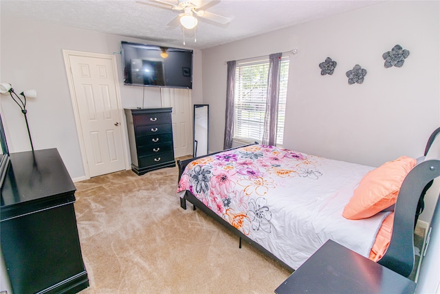 bedroom featuring a textured ceiling, light carpet, and ceiling fan