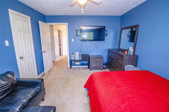 bedroom with ceiling fan, light colored carpet, and a textured ceiling