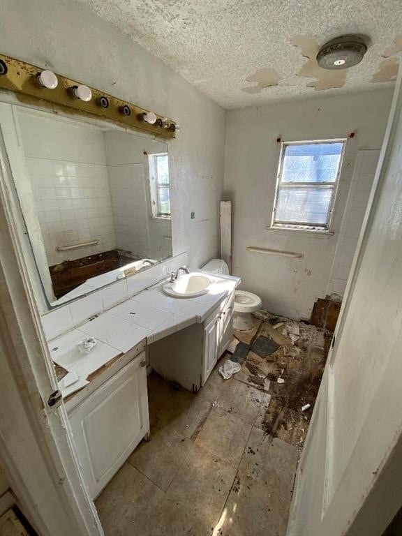 bathroom featuring vanity, plenty of natural light, toilet, and a textured ceiling