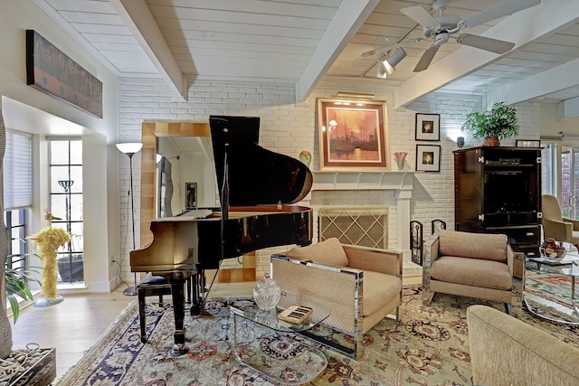 interior space featuring ceiling fan, beamed ceiling, brick wall, a fireplace, and light wood-type flooring