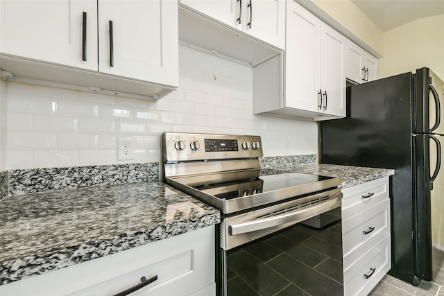 kitchen featuring white cabinets, backsplash, stainless steel range with electric stovetop, dark stone counters, and black fridge