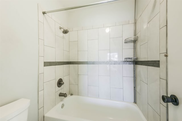 bathroom featuring tiled shower / bath combo and toilet