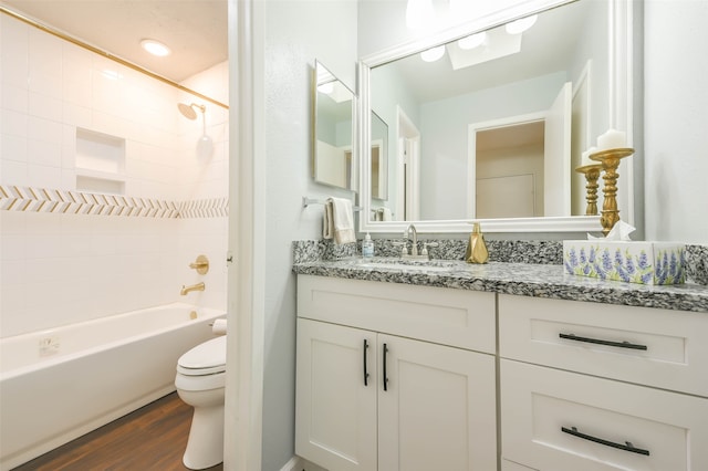 full bathroom featuring wood-type flooring, tiled shower / bath, vanity, and toilet