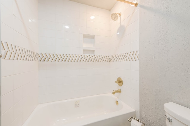 bathroom featuring tiled shower / bath combo and toilet