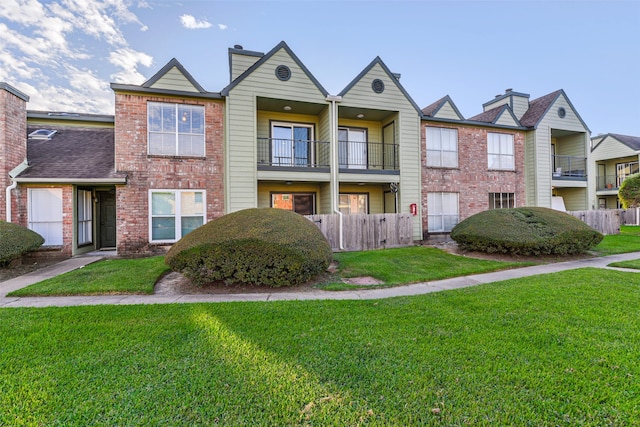 view of property featuring a balcony and a front lawn