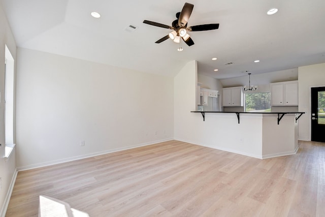 kitchen with white cabinetry, a kitchen breakfast bar, light hardwood / wood-style flooring, kitchen peninsula, and decorative light fixtures