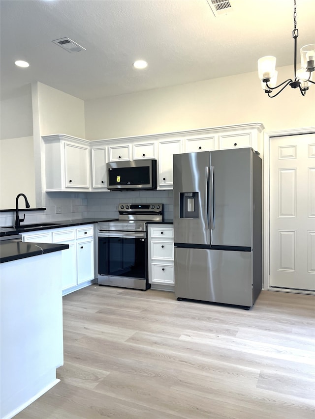 kitchen with white cabinetry, stainless steel appliances, an inviting chandelier, decorative light fixtures, and light wood-type flooring