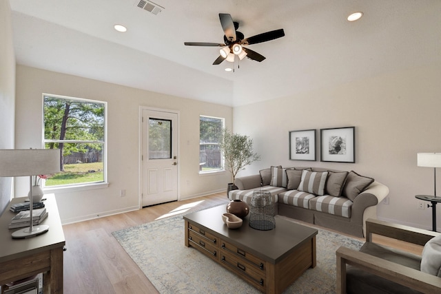 living room with a wealth of natural light, ceiling fan, light hardwood / wood-style floors, and vaulted ceiling