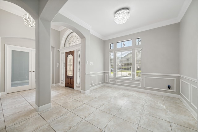 foyer with a notable chandelier, crown molding, and light tile patterned flooring