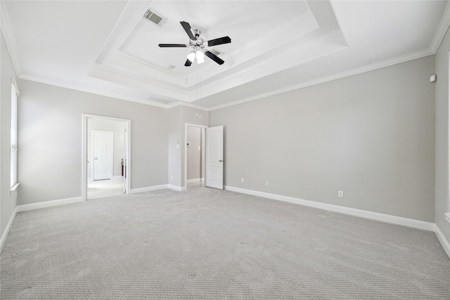 empty room featuring ornamental molding, ceiling fan, a raised ceiling, and light carpet