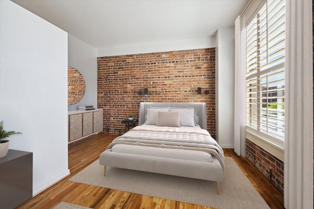 bedroom with brick wall and hardwood / wood-style flooring